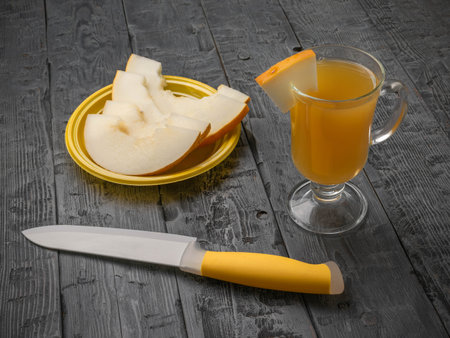 Refreshing Honeydew Melon Beverage with Sliced Fruit on Rustic Wooden Tableの写真素材