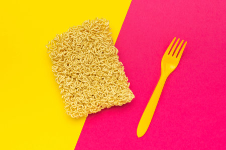 Instant Noodles with Yellow Fork on Vibrant Dual-Colored Backgroundの写真素材