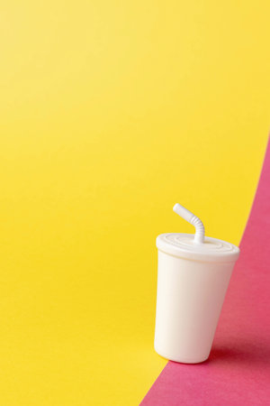 Minimalist White Cup with Straw on Vibrant Yellow and Pink Background for Creative Beverage Conceptsの写真素材