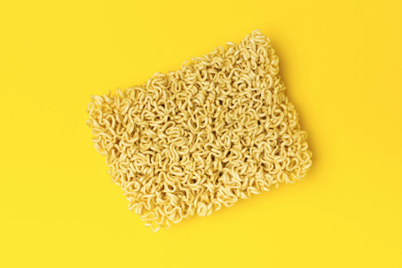 Square Block of Dry Instant Noodles on Bright Yellow Backgroundの写真素材