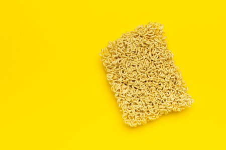 Dry Instant Noodles on Bright Yellow Background for Food and Culinary Conceptsの写真素材