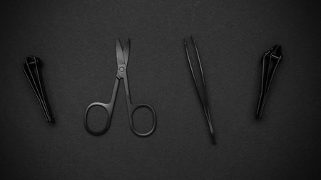 Minimalist Black Grooming Tools on Dark Background - Scissors, Tweezers, Nail Clippersの写真素材