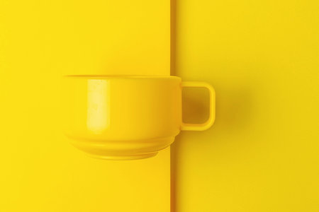 Minimalist Yellow Tea Cup on Monochrome Yellow Background Vibrant Color and Designの写真素材