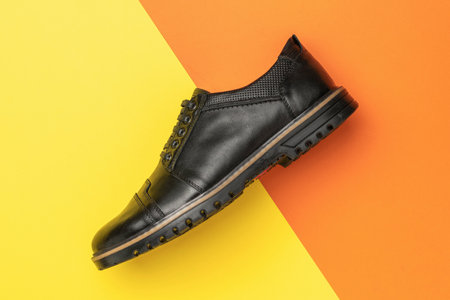 Black Leather Men's Dress Shoe on Vibrant Yellow and Orange Backgroundの写真素材