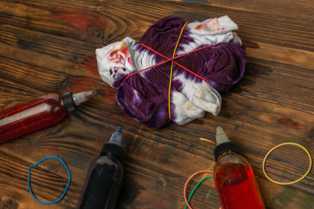Colorful Tie-Dye Process with T-Shirts and Dye Bottles on Wooden Tableの写真素材