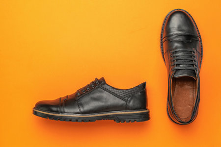 Black Leather Dress Shoes on Bright Orange Background Stylish Footwear for Mens Fashionの写真素材