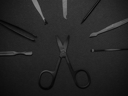 Black Surgical Instruments Arranged on Dark Background in Flat Lay Compositionの写真素材