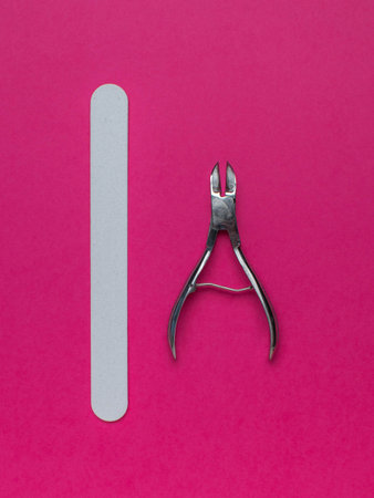 Nail Care Tools on Pink Background: Metal Clippers and White Emery Boardの写真素材