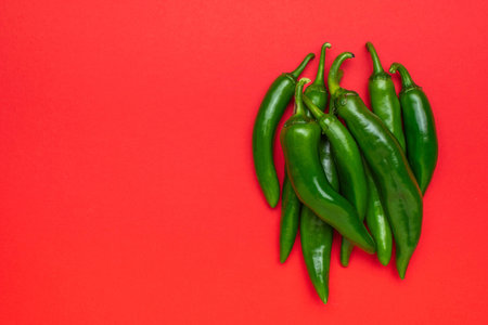 Green Chili Peppers on Vibrant Red Background: Fresh and Spicy Food Conceptの写真素材