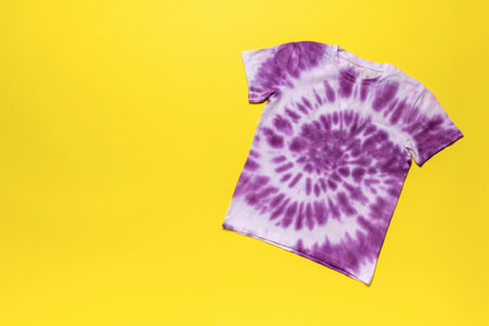 Vibrant Purple Tie-Dye T-Shirt on Bright Yellow Background - Trendy Fashion Stock Photoの写真素材