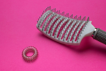 Hairbrush and Elastic Hair Band on Vibrant Pink Backgroundの写真素材