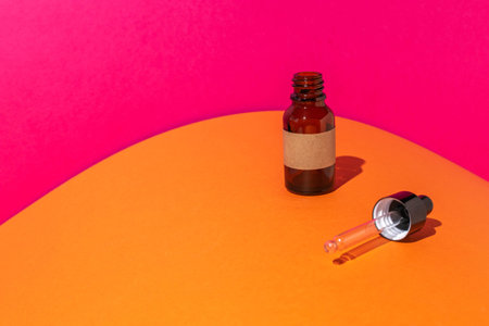 Minimalist Dropper Bottle with Bright Orange and Pink Background for Skincare or Aromatherapyの写真素材
