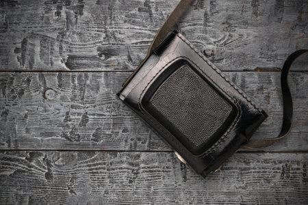 Vintage Black Leather Camera Case on Rustic Wooden Backgroundの写真素材
