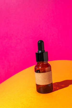 Brown Glass Dropper Bottle on Vibrant Yellow and Pink Background - Modern Minimalist Conceptの写真素材