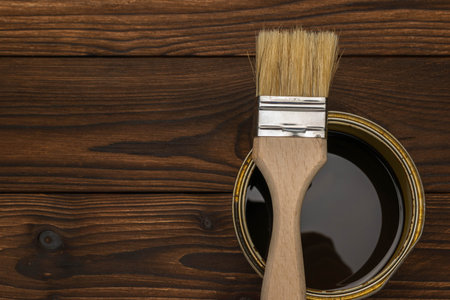 Close-Up of Paintbrush Dipped in Dark Stain on Wooden Surface - DIY and Home Improvement Conceptの写真素材