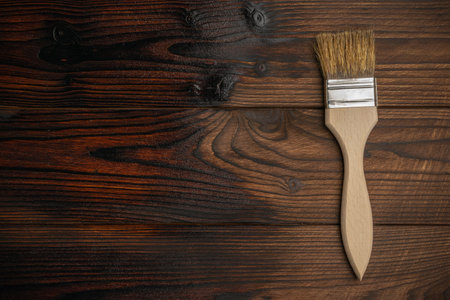 Wooden Surface with Paintbrush on Dark Wood Plank Background for DIY and Home Improvementの写真素材