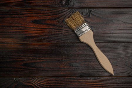 Paintbrush on Dark Wooden Surface Reflecting Rustic Charm and Detailed Craftsmanshipの写真素材