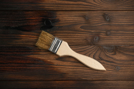 Wood Staining Process with Paintbrush on Dark Wooden Surface in Progressの写真素材