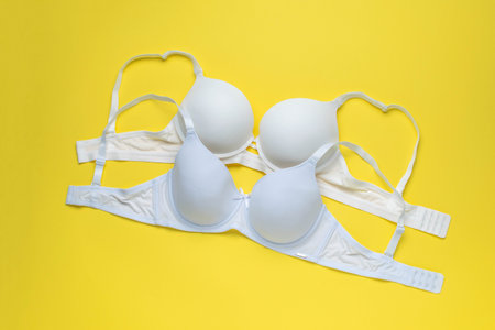 Three Stylish Bras on Yellow Background - Fashionable Lingerie Display in Minimalist Settingの写真素材