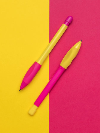 Colorful Pens on Vibrant Pink and Yellow Background Modern Office Suppliesの写真素材