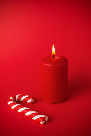 Festive Red Candle and Candy Cane on Red Background - Christmas Holiday Decorの写真素材
