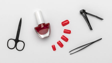 Red Nail Polish with Scissors, Hair Clips, Tweezer, and Faux Nails on White Backgroundの写真素材