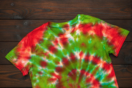Colorful Tie-Dye T-Shirt on Dark Wooden Background - Vibrant Summer Fashion Apparelの写真素材