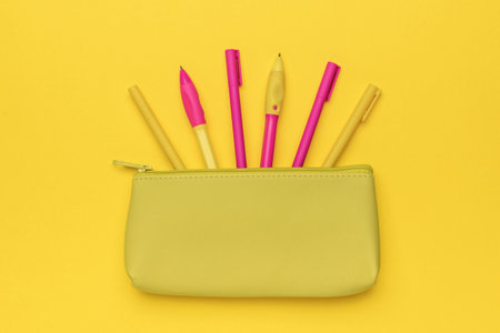 Yellow Pencil Case with Colorful Pens on Bright Yellow Backgroundの写真素材