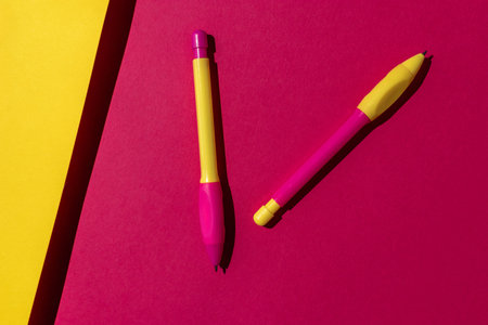 Vivid Contrast of Yellow and Pink Pens on Bold Red and Yellow Backgroundの写真素材