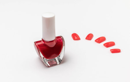 Red Nail Polish Bottle with Artificial Nails on White Background - Beauty and Fashion Stock Photoの写真素材
