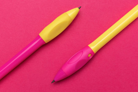 Colorful Yellow and Pink Pens on Vibrant Red Background for Office and School Suppliesの写真素材