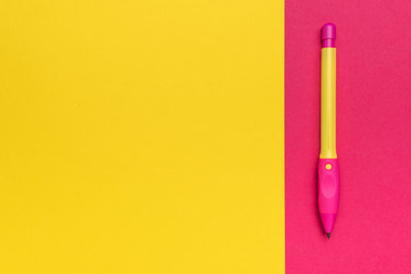 Vibrant Pink and Yellow Pen on a Colorful Split Background for Creative Stationery Conceptsの写真素材