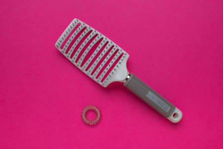 Modern Pink Hairbrush with Spiral Hair Tie on Vibrant Pink Background - Haircare and Styling Toolsの写真素材