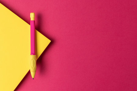 Bright Yellow Pen on Bold Pink and Yellow Geometric Background - Modern Office Suppliesの写真素材