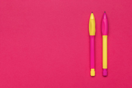 Bright Pink and Yellow Pens on Vibrant Red Backgroundの写真素材