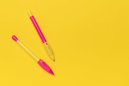 Bright and Colorful Pink and Yellow Pens on Vibrant Yellow Backgroundの写真素材