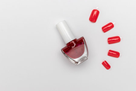 Red Nail Polish Bottle with Fake Nail Tips on White Backgroundの写真素材