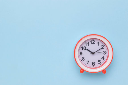 Classic Red Framed Analog Clock on Light Blue Backgroundの写真素材