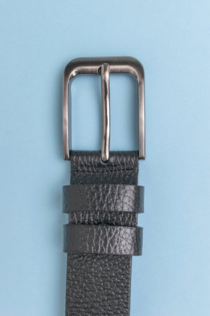 Black Leather Belt with Silver Buckle on Blue Background - High-Quality Fashion Accessory Imageの写真素材