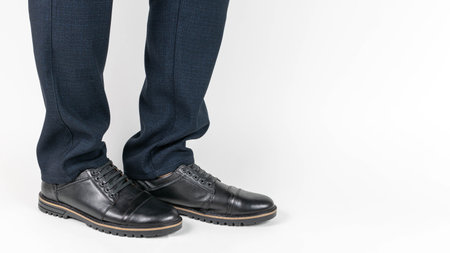 Close-Up of Businessman's Legs in Formal Pants and Black Leather Shoes on White Backgroundの写真素材