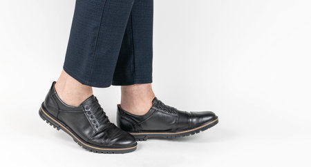 Close-Up of Men's Black Leather Shoes with Professional Navy Pants on White Backgroundの写真素材