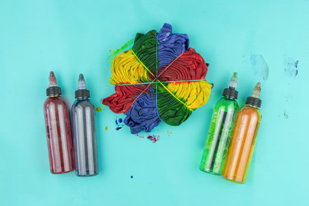 Colorful Tie-Dye Shirt with Dye Bottles on a Light Blue Background for Creative Craft Projectsの写真素材