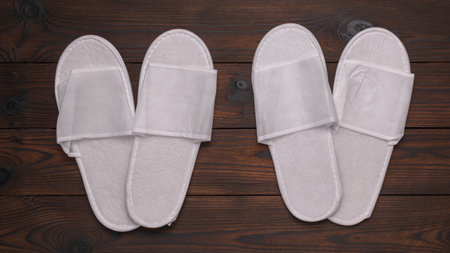 White Disposable Spa Slippers on Wooden Background - Minimalist Hotel Amenitiesの写真素材