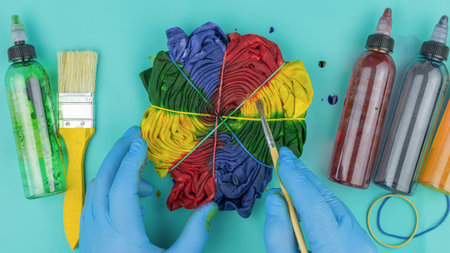 Colorful Tie-Dye Shirt Creation with Gloves and Paint on Teal Backgroundの写真素材