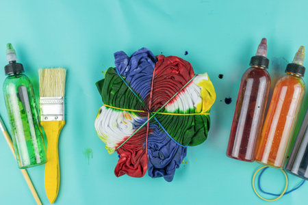 Colorful Tie-Dye Art Supplies with Fabric, Paint Bottles, and Brush on Blue Backgroundの写真素材