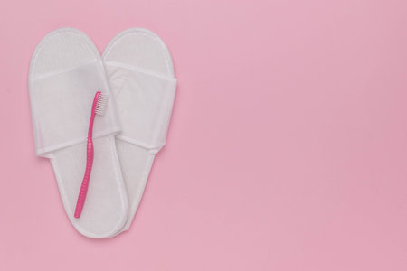 Cozy White Slippers and Pink Toothbrush on Pastel Pink Backgroundの写真素材