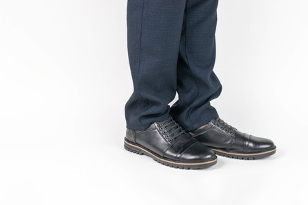 Businessman's Legs in Formal Trousers and Black Leather Shoes on White Backgroundの写真素材