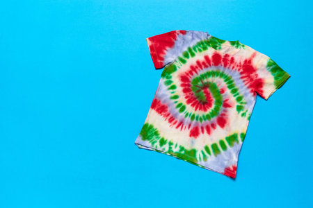 Colorful Spiral Tie-Dye T-Shirt on Blue Background, Vibrant Fashion Apparel, Groovy 60s Style Clothing, Retro Tie-Dye Patterns, Hipster Summer Outfitの写真素材