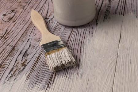 Paintbrush and White Paint on Wooden Surface: Home Renovation and DIY Conceptの写真素材