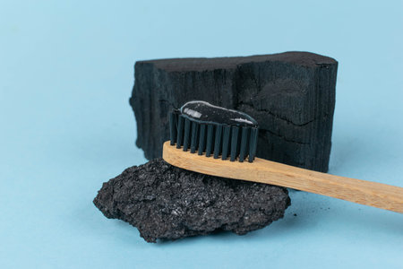 Black Charcoal Toothpaste on Bamboo Toothbrush with Charcoal Backgroundの写真素材